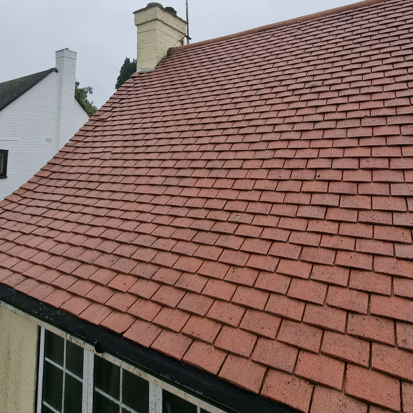 The same cottage roof after moss and lichen removal, showing clean clay tiles