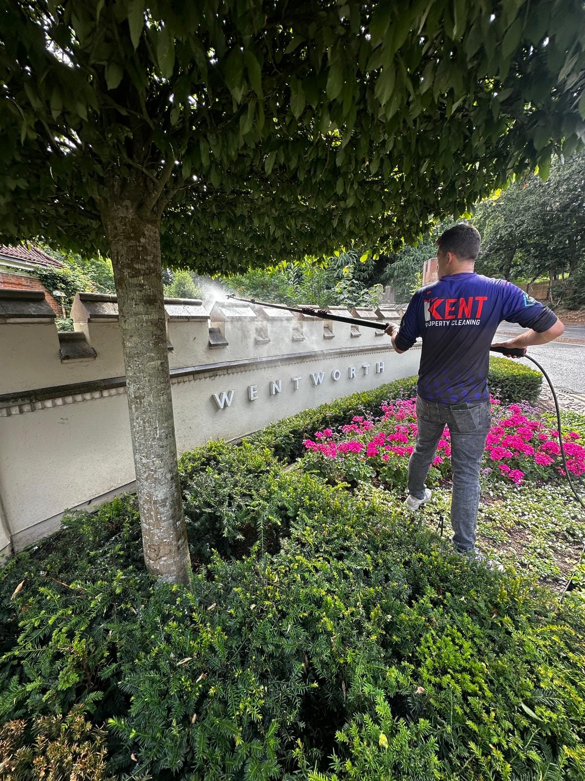 A Kent Property Cleaning operative pressure washing a stone estate wall